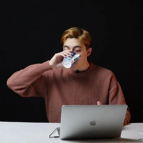 me drinking water and looking at macbook in cool sweater